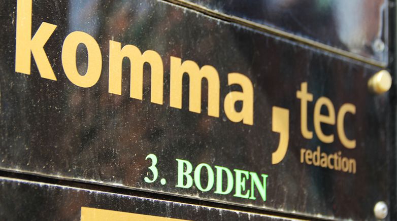 Das Bild zeigt ein Schild des Unternehmens " komma,tec redaction"